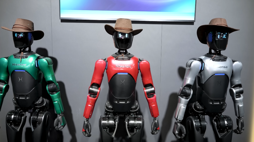 Afbeelding: Drie humanoïde robots op een beursstand tijdens CES 2026